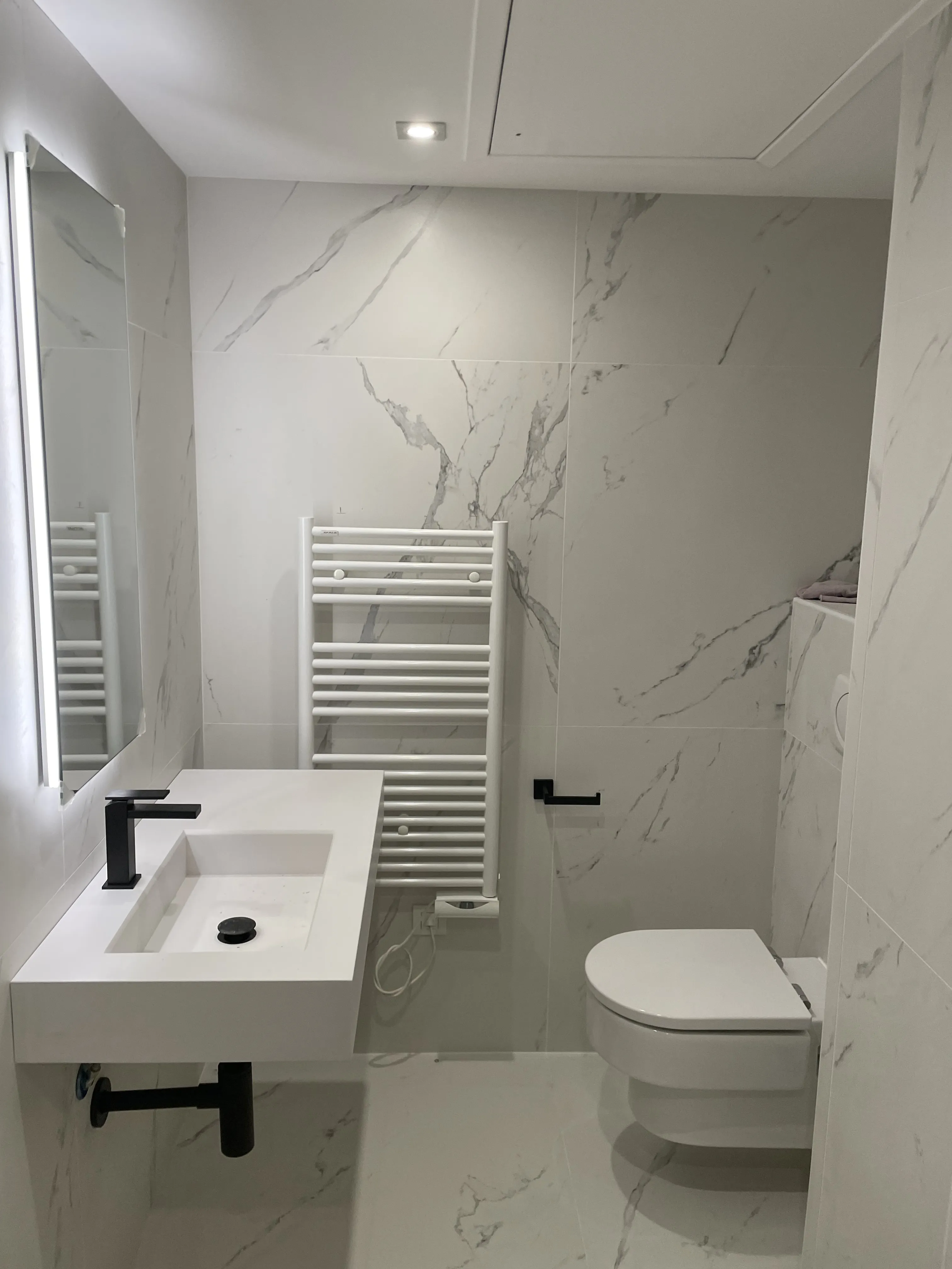 Bagno con rivestimento in marmo e rubinetteria nera, finiture di pregio